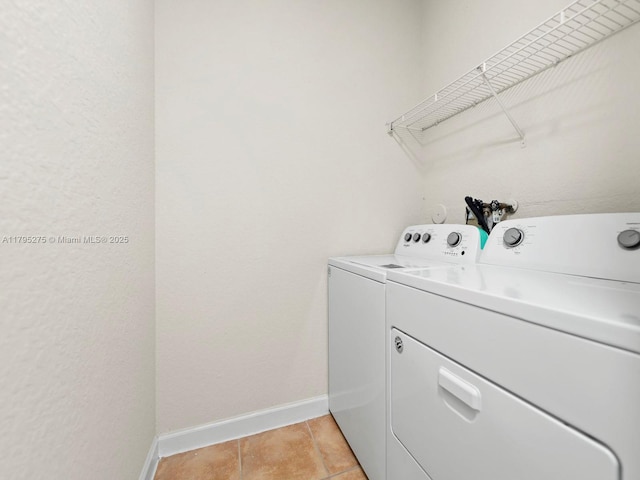 washroom with baseboards, light tile patterned floors, laundry area, and washer and clothes dryer