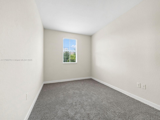 carpeted spare room featuring baseboards