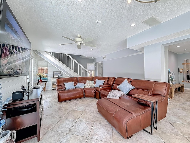 living room featuring stairway, ceiling fan, light tile patterned floors, and a textured ceiling
