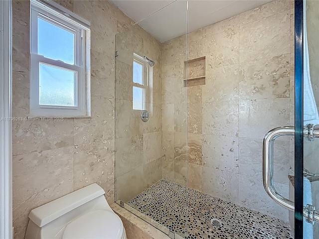 bathroom featuring a stall shower, toilet, and tile walls