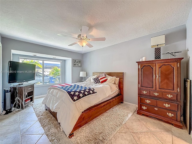 bedroom with a textured ceiling, light tile patterned floors, a ceiling fan, and baseboards