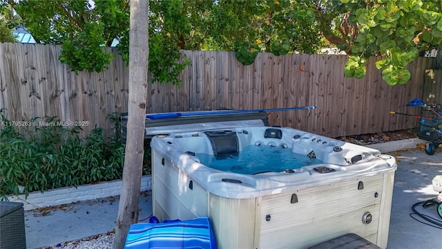 view of patio with a hot tub and fence