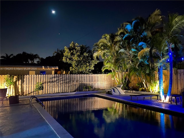 pool at twilight featuring a fenced backyard and a patio