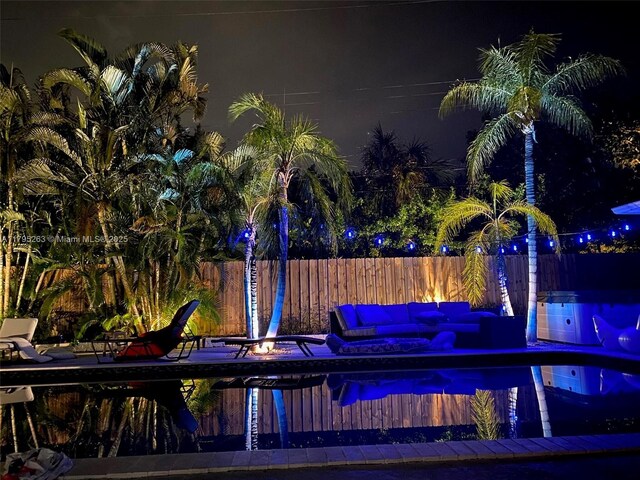 pool at night featuring fence
