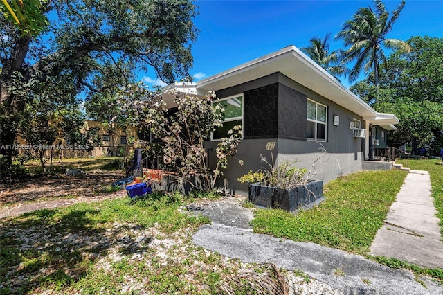 view of side of home with stucco siding and fence