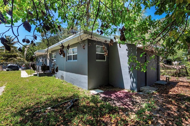 view of property exterior featuring a lawn, fence, and stucco siding