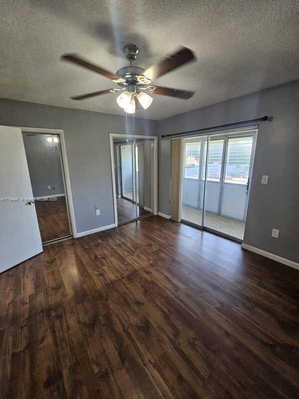 unfurnished bedroom featuring access to outside, a textured ceiling, and wood finished floors