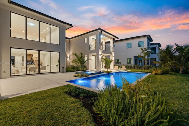 12060 NW 67th Ct, Parkland, FL 33076 - pool at dusk featuring a patio, an outdoor pool, and a lawn