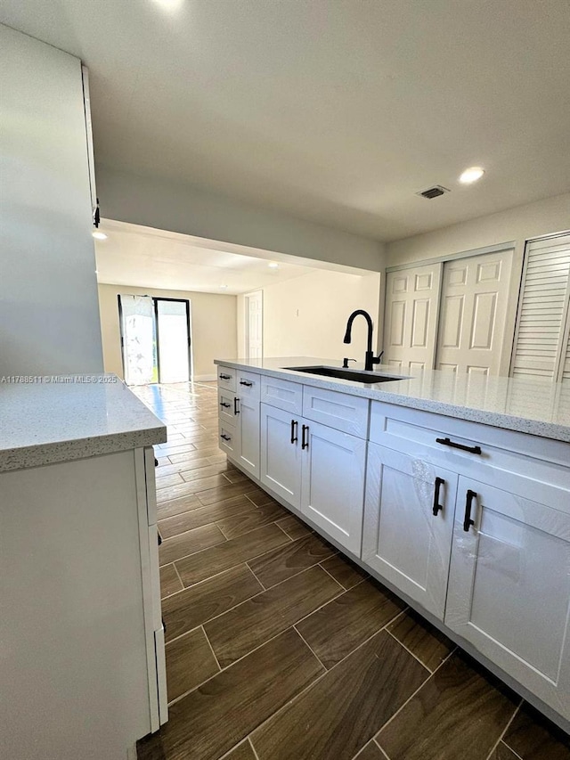 1770 NW 109th St, Miami, FL 33167 - kitchen featuring wood tiled floor, visible vents, a sink, white cabinets, and recessed lighting