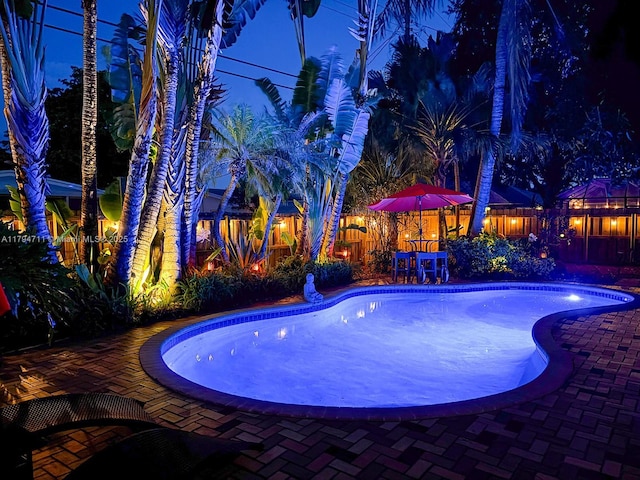 4400 NE 13th Ave, Oakland Park, FL 33334 - pool at night with a fenced in pool, a fenced backyard, and a patio area