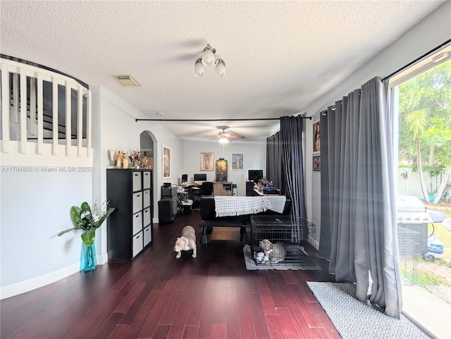 living area with visible vents, wood finished floors, baseboards, a textured ceiling, and arched walkways