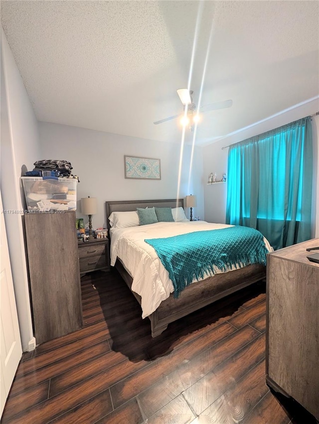 bedroom with a ceiling fan, dark wood finished floors, and a textured ceiling