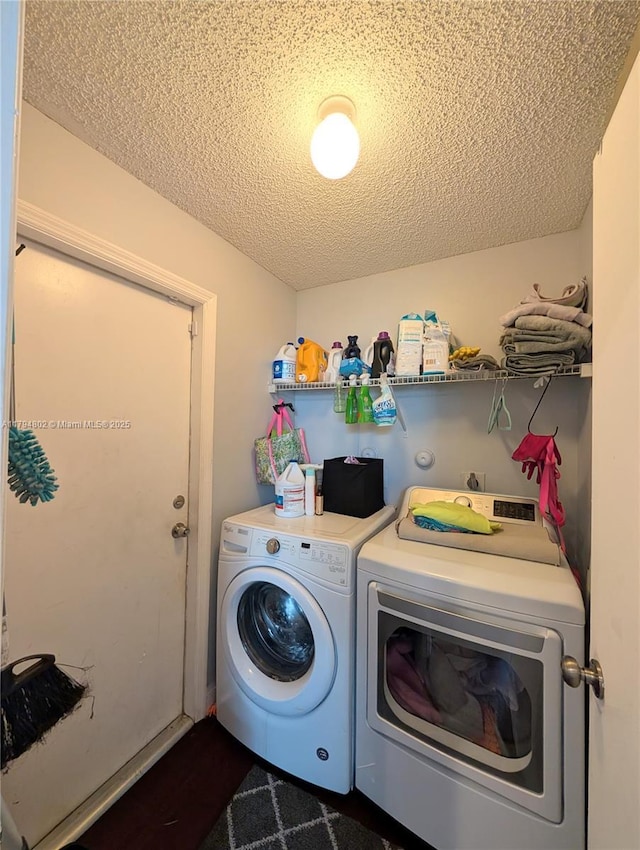 washroom featuring separate washer and dryer, laundry area, and a textured ceiling