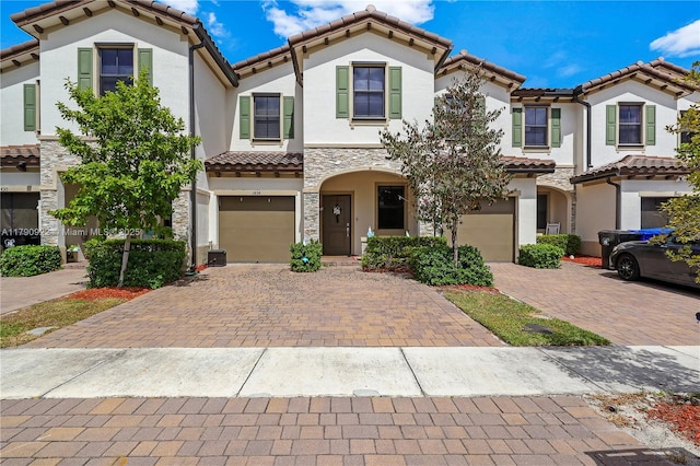 mediterranean / spanish house featuring a tiled roof, an attached garage, driveway, and stucco siding
