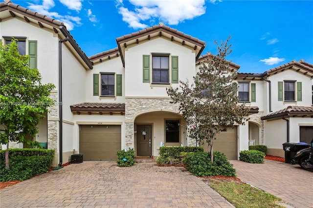 mediterranean / spanish-style home featuring a garage, a tiled roof, driveway, and stucco siding