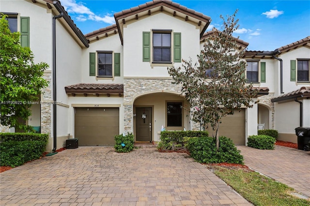 view of front of property featuring a garage, a tiled roof, driveway, and stucco siding