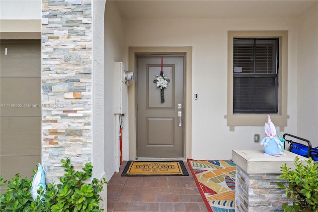 view of exterior entry featuring stucco siding and stone siding