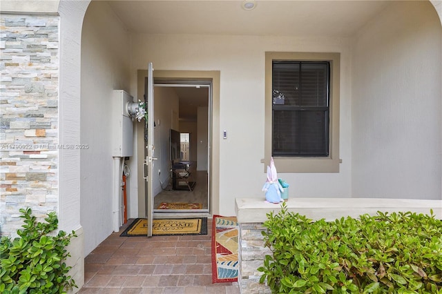 doorway to property featuring stone siding and stucco siding