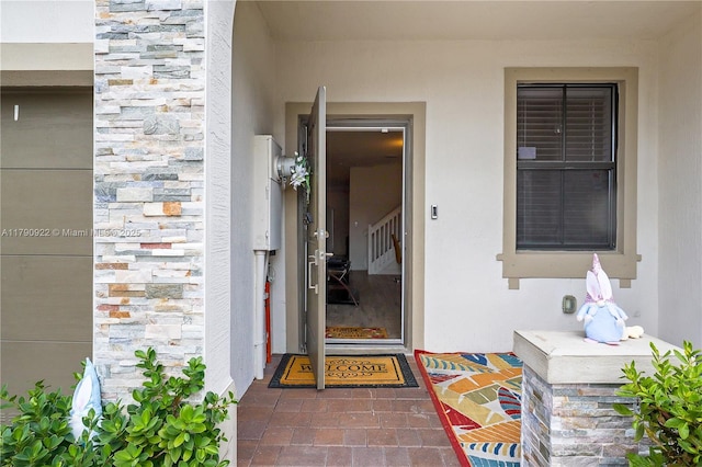 property entrance featuring stucco siding and stone siding