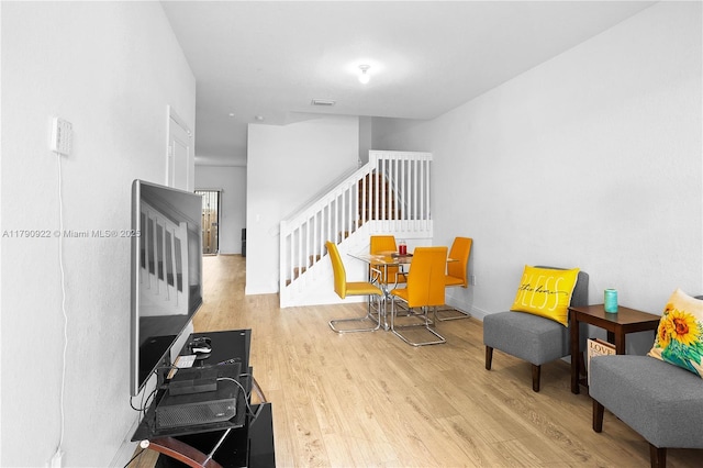 living area featuring stairs, visible vents, and wood finished floors