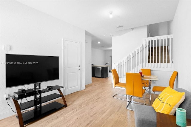 living room with light wood-style floors, baseboards, visible vents, and stairway
