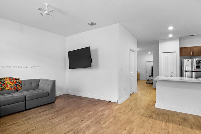 living area featuring a ceiling fan, visible vents, light wood-type flooring, baseboards, and recessed lighting