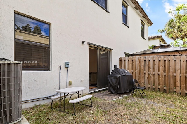 back of house with central AC, stucco siding, and fence