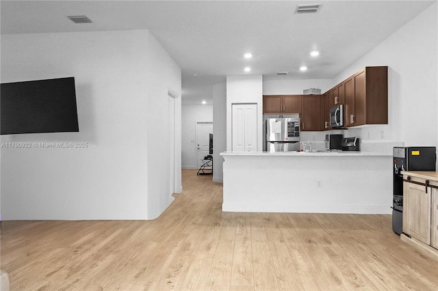 kitchen with light wood-style floors, appliances with stainless steel finishes, light countertops, and visible vents