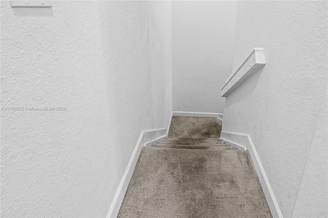 stairway with baseboards, carpet flooring, and a textured wall