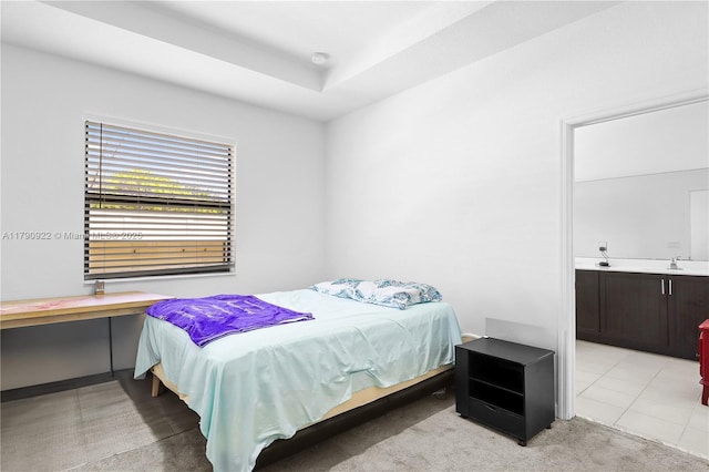 bedroom with a sink, light carpet, and ensuite bath