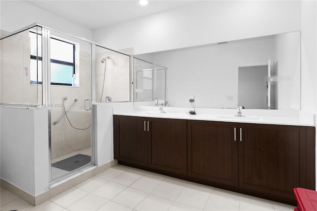 full bath with a sink, tile patterned floors, a shower stall, and double vanity