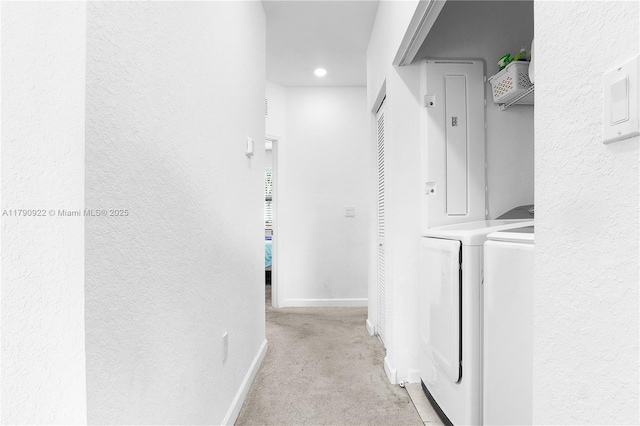 interior space with baseboards, a textured wall, light carpet, and washing machine and clothes dryer