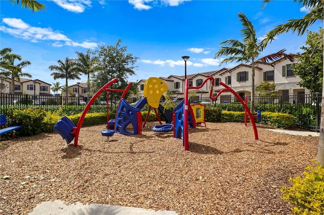 community play area featuring fence and a residential view