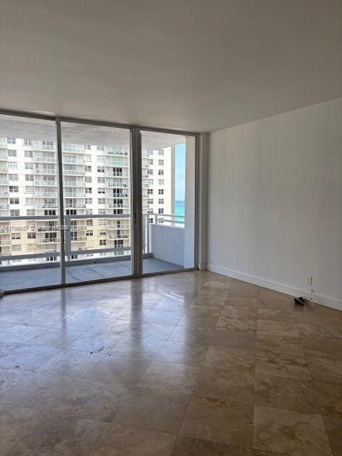 unfurnished room with baseboards and a wall of windows