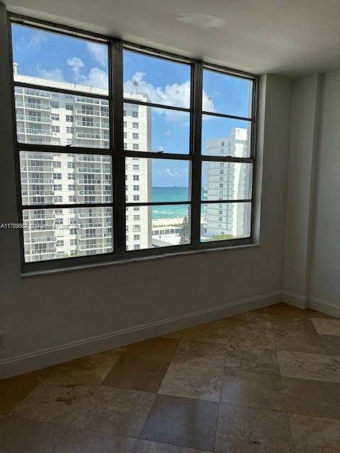 spare room with baseboards and a water view