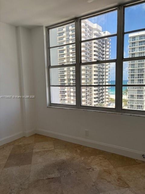 unfurnished room with a view of city and baseboards