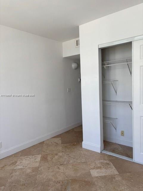 unfurnished bedroom featuring baseboards, visible vents, and a closet