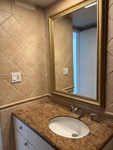 bathroom featuring vanity and tile walls