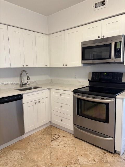 kitchen with visible vents, light countertops, white cabinets, a sink, and appliances with stainless steel finishes