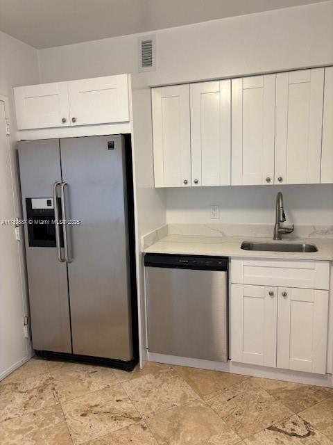 kitchen featuring white cabinets, a sink, light countertops, stainless steel appliances, and visible vents