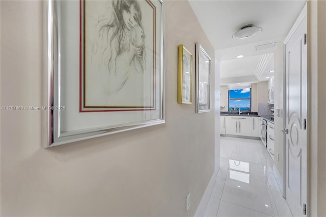 hallway featuring baseboards, a sink, and light tile patterned flooring