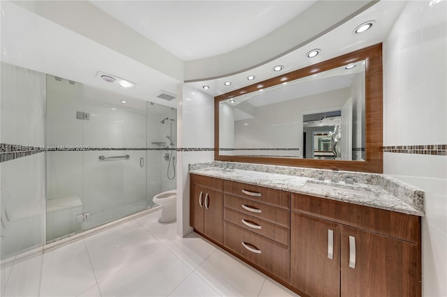 full bath featuring a sink, double vanity, toilet, tile patterned floors, and a stall shower