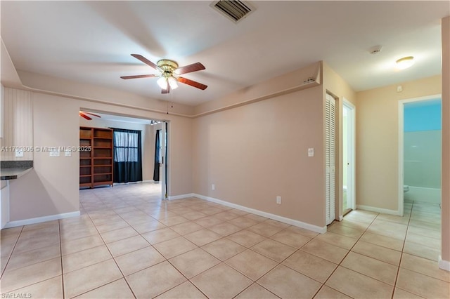 unfurnished room featuring a ceiling fan, baseboards, visible vents, and light tile patterned floors