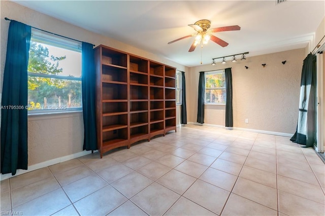 spare room with track lighting, a textured wall, baseboards, ceiling fan, and light tile patterned floors
