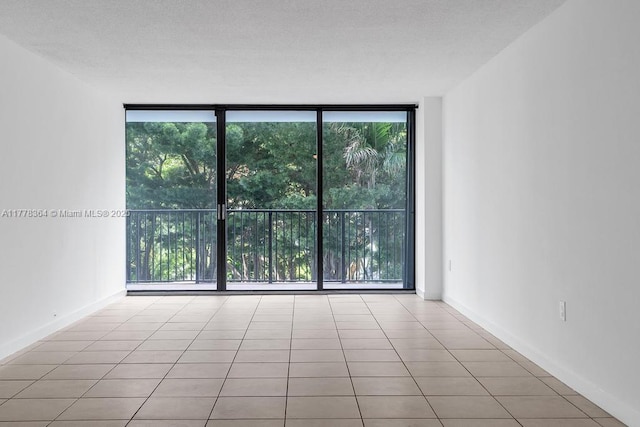 empty room featuring floor to ceiling windows, a healthy amount of sunlight, and tile patterned flooring