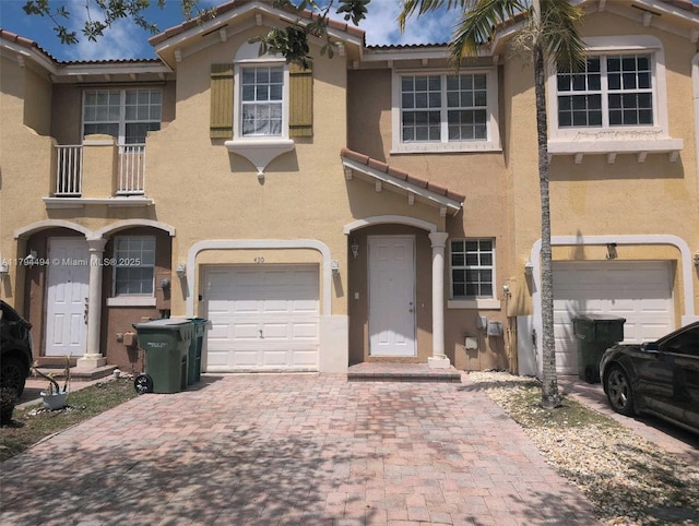 view of front facade featuring decorative driveway, an attached garage, a tile roof, and stucco siding