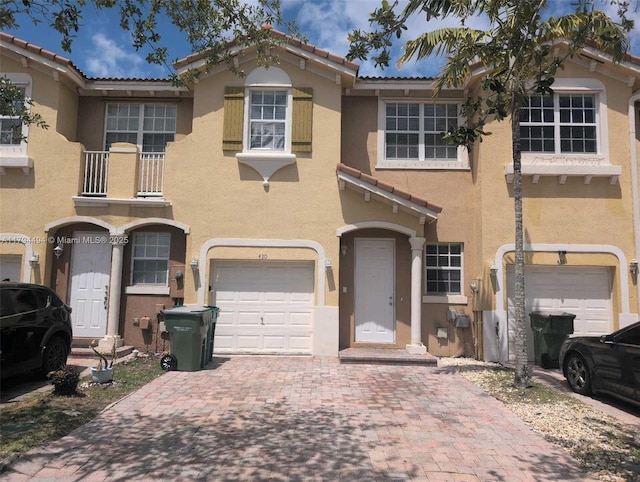view of front of house featuring a garage, stucco siding, a balcony, and a tile roof