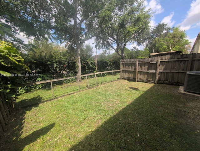 view of yard featuring a fenced backyard and central AC