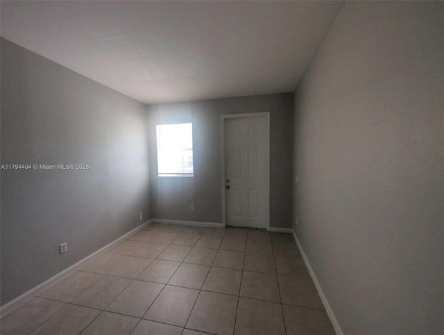 spare room with baseboards and light tile patterned flooring