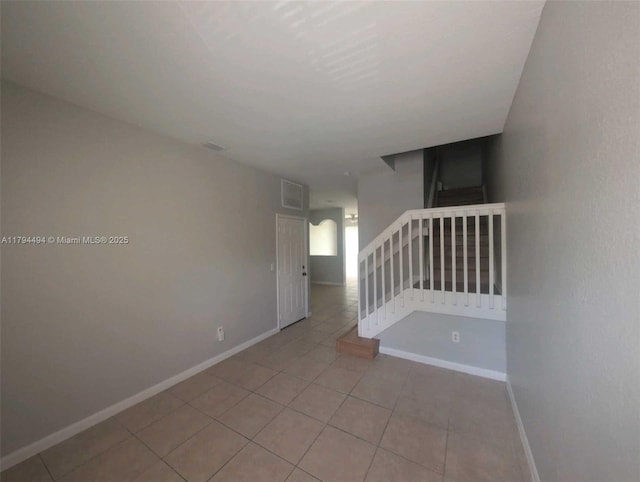spare room featuring baseboards, visible vents, and tile patterned flooring